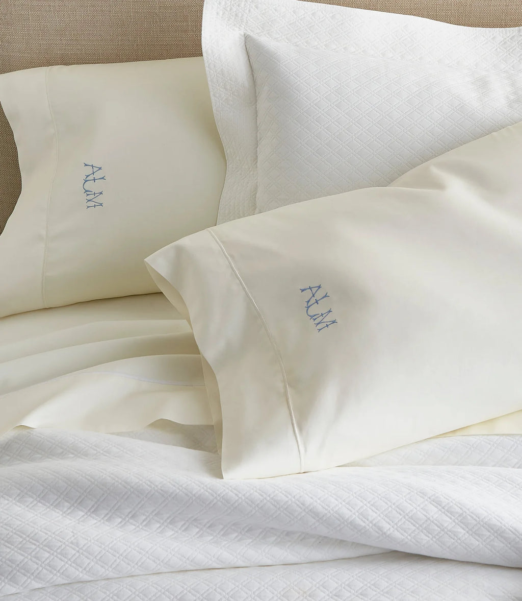 White pillows with embroidered initials on a bed